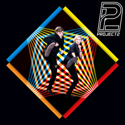 A black square with a colourful graphic diamond in the middle. Katy and Chris are frozen in action movie kicks. The clean science fiction logo for Project2 is in the upper right corner.